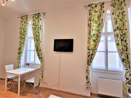 een kamer met 2 ramen, een tafel en een tv bij Reznicka Apartments in Praag