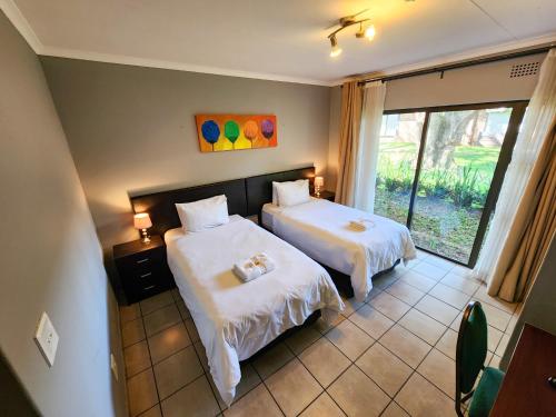 a hotel room with two beds and a window at The Venue Country Hotel & Spa in Hartbeespoort