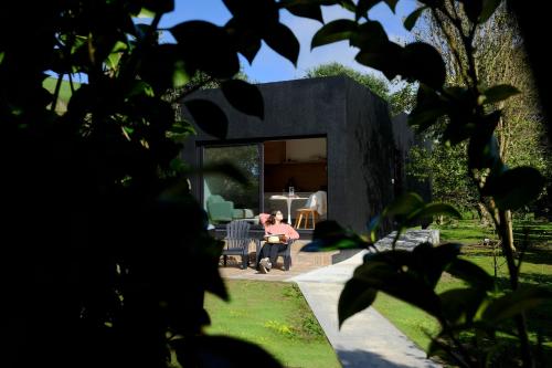 a woman sitting in a chair in a yard at Villa Várzea - The Black Cabin in Várzea