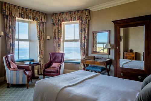 a hotel room with a bed and two chairs and a mirror at Mullion Cove Hotel & Spa in Mullion