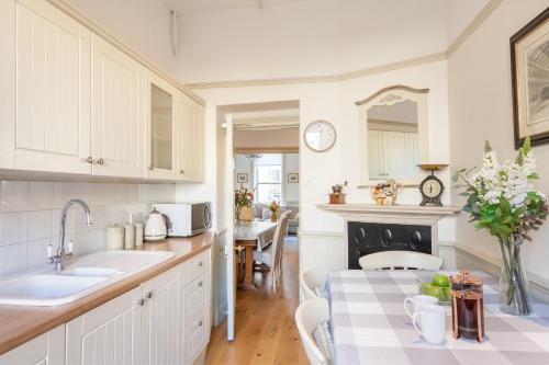 a kitchen with white cabinets and a table with a table cloth at City Centre Stunning House-Roman Baths - 3min walk - 4 Bedrooms in Bath