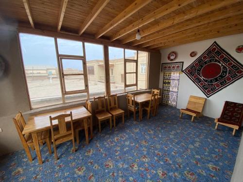 a dining room with tables and chairs and a large window at Naqqosh in Khiva