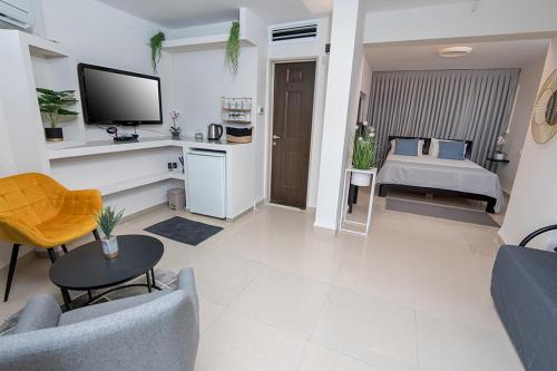 a living room with a tv and a couch and a table at אדם וחווה - סוויטות מפנקות עם ג'קוזי פרטי ובריכה במתחם מול נוף גלילי מושלם in Gornot HaGalil