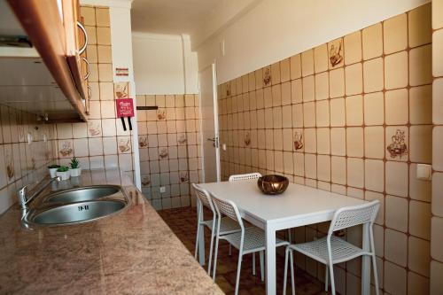 eine Küche mit einer Spüle sowie einem Tisch und Stühlen in der Unterkunft SUNRISE ALOJAMENTO in Peniche