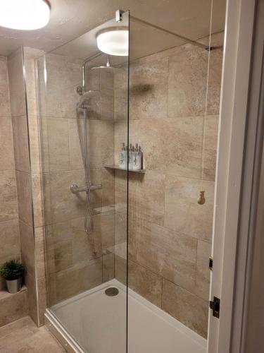 a shower with a glass door in a bathroom at The Granary Corris on the edge of the Dyfi Forest in Corris