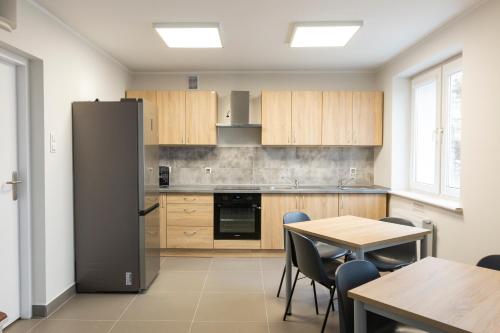 a kitchen with a refrigerator and a table and chairs at Dom Studencki Komenik in Leszno
