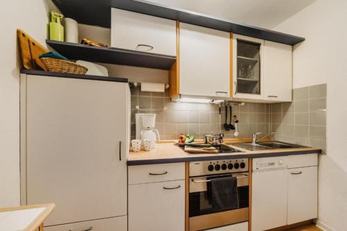 uma cozinha com armários brancos e um forno com placa de fogão em kleiner Wumbi Braunlage em Braunlage