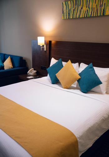 a hotel room with a bed with blue and yellow pillows at Best Western Premier Muscat in Muscat