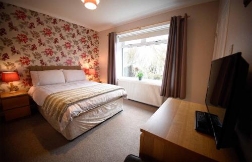 a small bedroom with a bed and a window at Fladda Chuain Holiday Home in Kilmuir