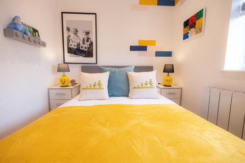 um quarto com uma cama grande com lençóis amarelos em Legoland Family Fun - Upscale Two Bedroom Apt Near Tube Station with Kid-Friendly Amenities em Slough