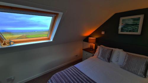a bedroom with a bed and a large window at Fladda Chuain Holiday Home in Kilmuir