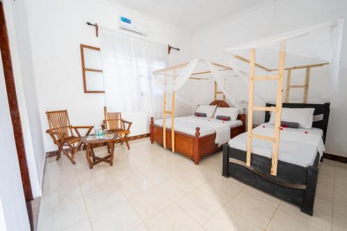 a bedroom with two beds and a table and chairs at Savi House Nungwi in Nungwi