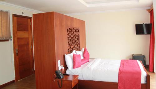 a hotel room with a bed with red and white pillows at Lake Elementaita Mountain Lodge in Nakuru