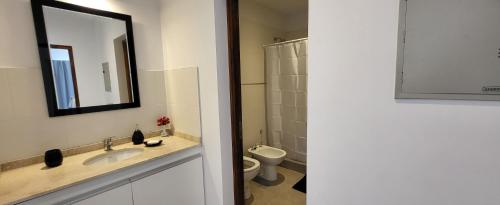 y baño con lavabo, aseo y espejo. en Complejo Azahar en Godoy Cruz