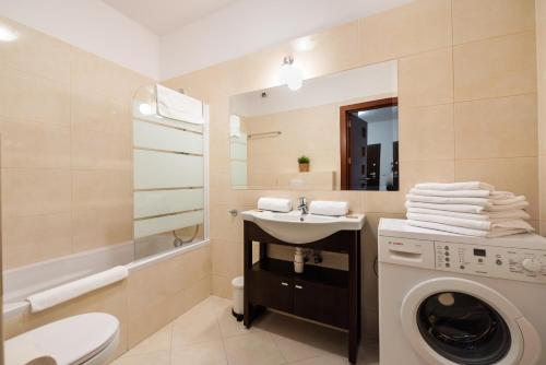 a bathroom with a washing machine and a sink at Wola Sunset Apartment FREE Parking in Warsaw