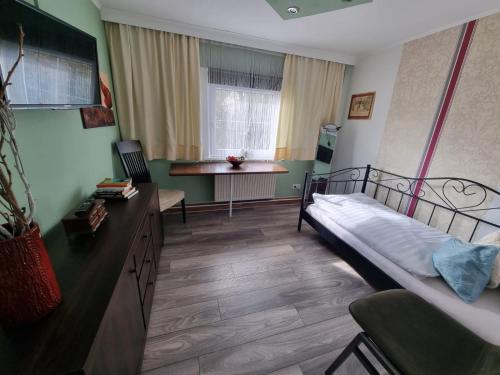 a bedroom with a bed and a desk and a table at Forsthaus-Ferienhotel am Dobrock in Wingst