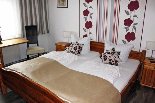 a bedroom with a large bed with white sheets and pillows at Forsthaus-Ferienhotel am Dobrock in Wingst