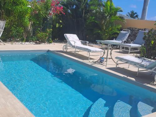 a blue swimming pool with chairs and a table at Tropical in Orient Bay French St Martin