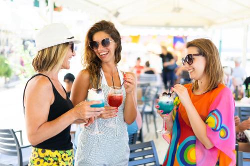 three women laughing while drinking cocktails at an event at Mistral Hotel - For Solo Travelers in Maleme