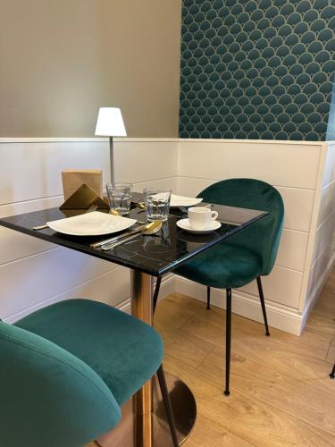a table with two green chairs and a table with glasses at 7th Floor Suite in Naples