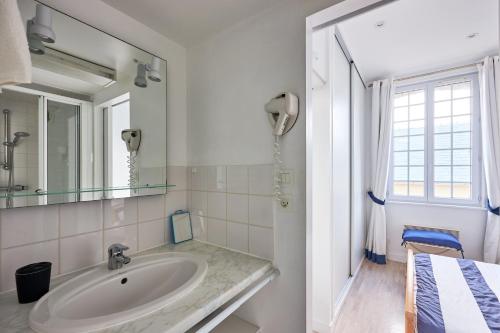 een witte badkamer met een wastafel en een spiegel bij Château de Chimay - Appt en front de mer in Barneville-Carteret