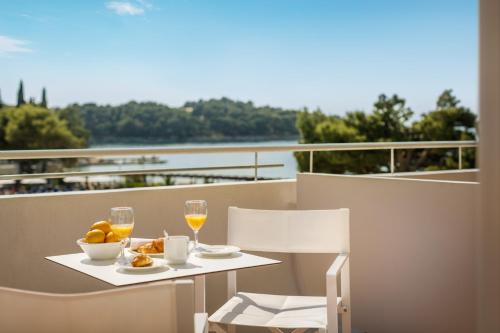 a table with two glasses of wine and a bowl of fruit at Remisens Hotel Albatros-All inclusive in Cavtat