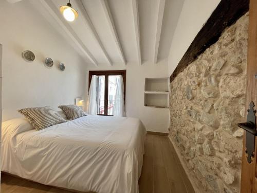 a bedroom with a white bed and a stone wall at Casa en el Puerto de Denia in Denia