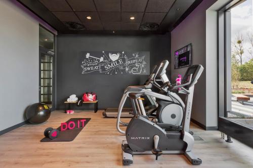 a fitness room with a treadmill and a gym at Moxy Katowice Airport in Pyrzowice