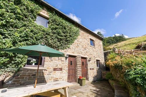 a green umbrella sitting on a wooden table in front of a building at Ash Cottage in Hope