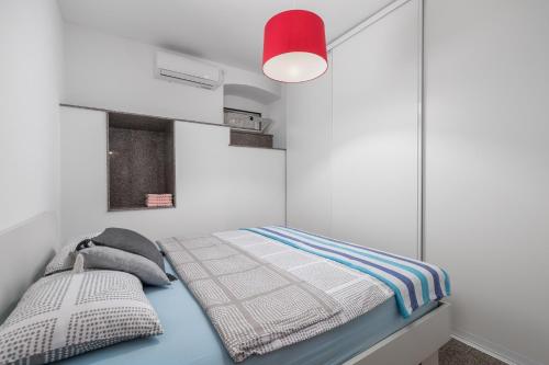 a small bedroom with a bed with a red lamp at Apartment Thor in Opatija