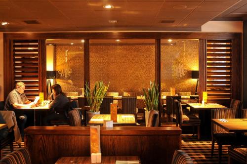 two people sitting at tables in a restaurant at Mondo Hotel in Coatbridge