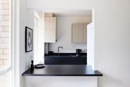 a kitchen with a black counter and a sink at The London Escape - Modish 1BDR Flat in London