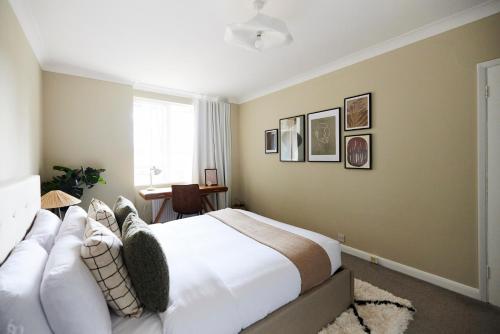 a bedroom with a large white bed and a window at The London Escape - Modish 1BDR Flat in London