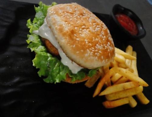 a hamburger and french fries on a black plate at Corbett VEDA INN in Rāmnagar