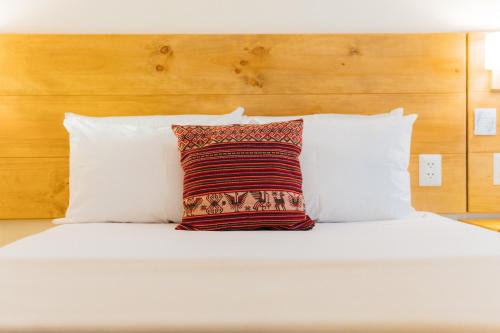 a bed with white pillows and a red pillow at Cooper Hotel Boutique in Cusco