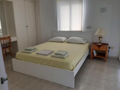 a bedroom with a bed with two towels on it at Pangeras Apartments in Pissouri