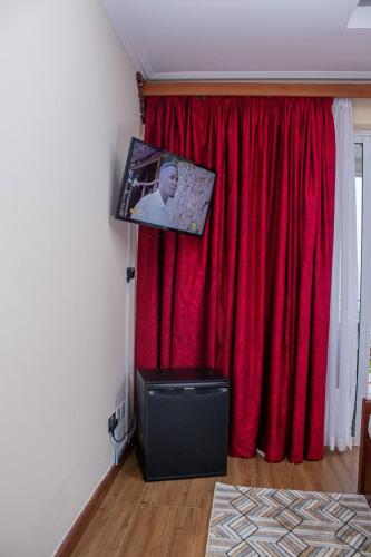 a room with a red curtain and a flat screen tv at Lake Elementaita Mountain Lodge in Nakuru