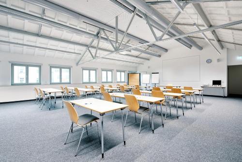 uma sala de aula com mesas e cadeiras numa sala em Bielefeld JBB Jugendgästehaus em Bielefeld