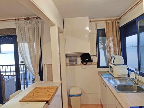 een keuken met een wastafel en een aanrecht met een magnetron bij ShoreHouse Apartamento Primera linea Playa Honda in Playa Honda