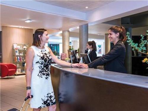 Deux femmes serrent la main à un comptoir dans un magasin dans l'établissement La Villa Du Lac- 3 rooms for 6 people, à Divonne-les-Bains