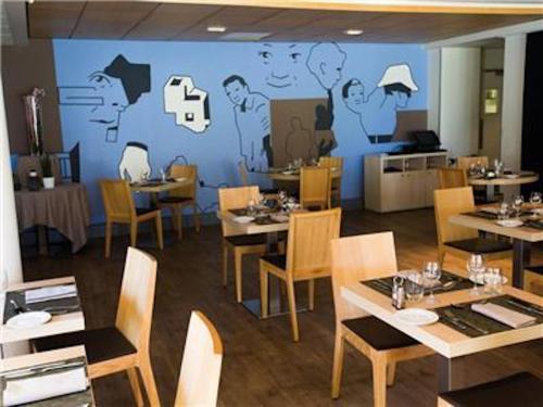 a restaurant with tables and chairs and a wall with a mural at La Villa Du Lac- 3 rooms for 6 people in Divonne-les-Bains