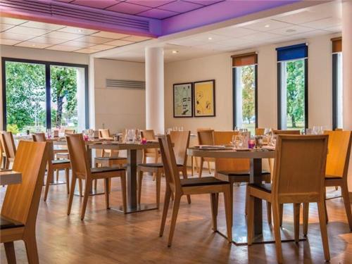 a dining room with tables and chairs and windows at La Villa Du Lac- 3 rooms for 6 people in Divonne-les-Bains