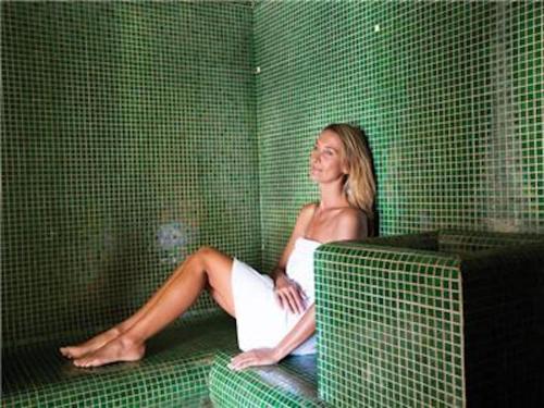 a woman sitting on a couch in a green room at La Villa Du Lac- 3 rooms for 6 people in Divonne-les-Bains