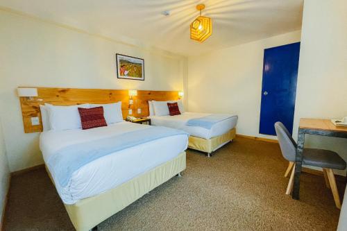 a hotel room with two beds and a desk and a desk at Cooper Hotel Boutique in Cusco