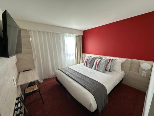 um quarto de hotel com uma cama grande e uma parede vermelha em Hôtel Akena Chauray-Niort em Chauray