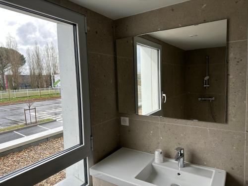 a bathroom with a sink and a mirror and a window at Hôtel Akena Chauray-Niort in Chauray