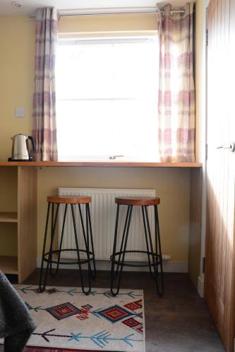 a kitchen with two bar stools under a window at Room at the Back, 2 George Street in Avoch