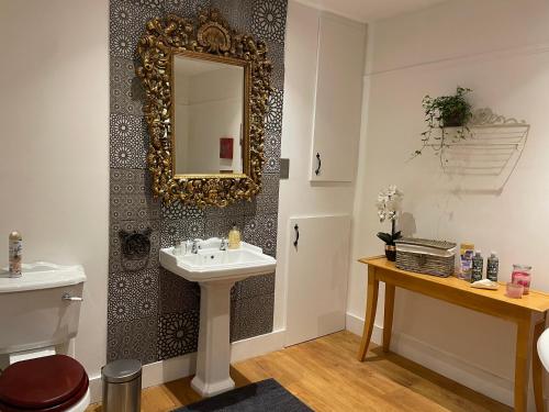 a bathroom with a sink and a mirror on a wall at Traditional English 4 bedroom home in Greenwich in Plumstead