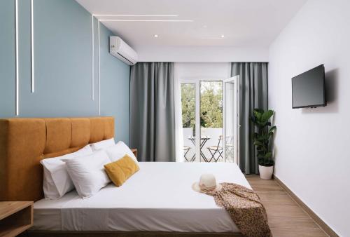 Ermis Luxury Suites & Apartments في أمودارا هيراكليو: غرفة نوم بسرير ابيض وتلفزيون على الحائط