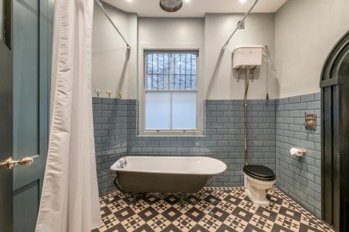 een badkamer met een bad en een raam bij The Dream Factory - London Bridge- by Frankie Says in Londen